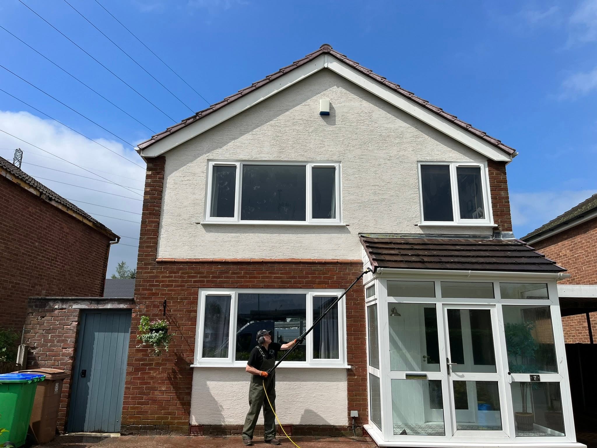 Technician cleaning windows and render with a water-fed pole