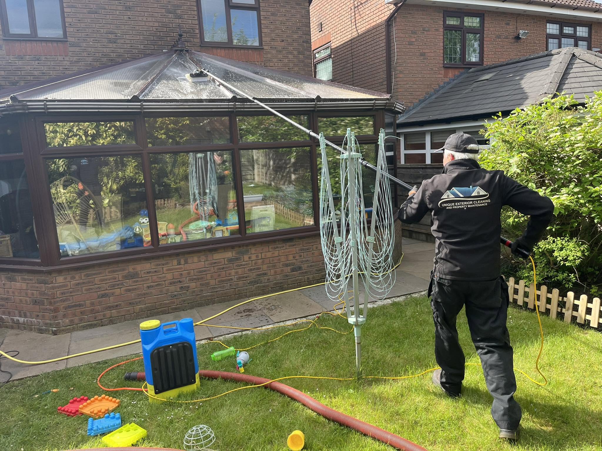 Unique Exterior Cleaning team member in branded jacket cleaning a conservatory roof