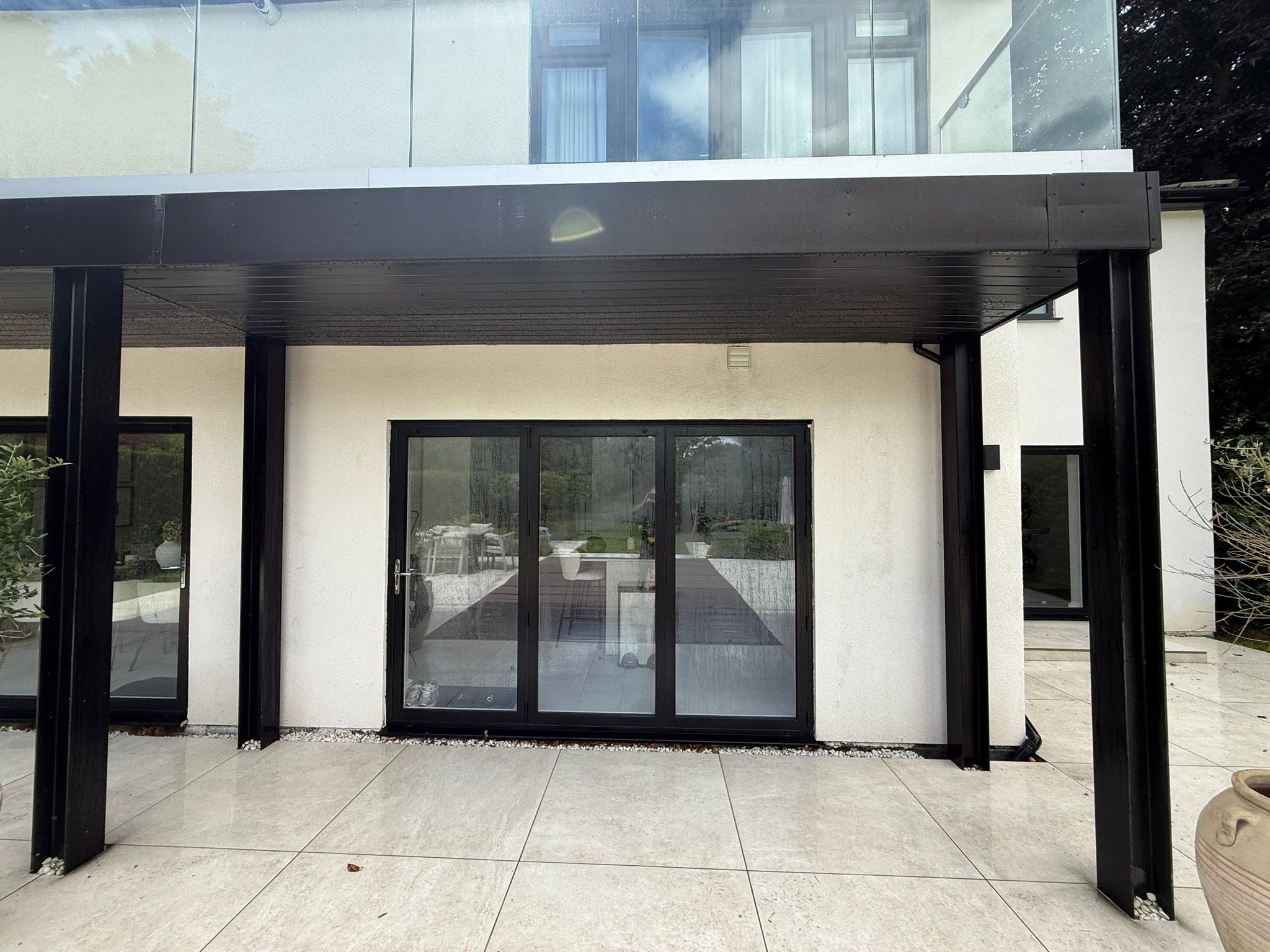 Modern black-framed home with cleaned patio and render